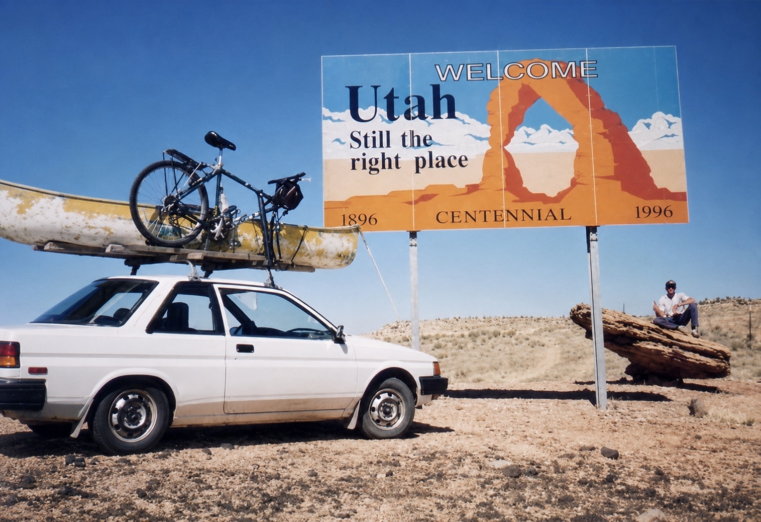 Tim beside a Welcome to Utah sign with a Toyota carrying a canoe and bicycle during a 1996 western road trip
