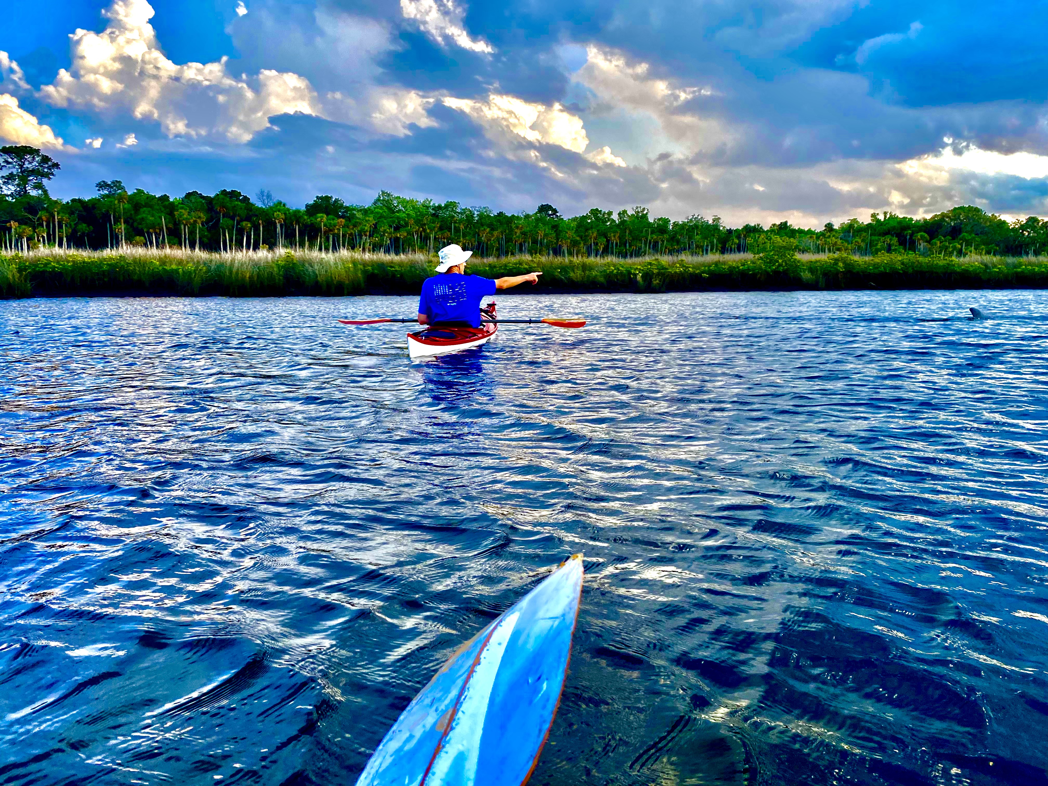Kayaking across open water near Aripeka under dramatic clouds
