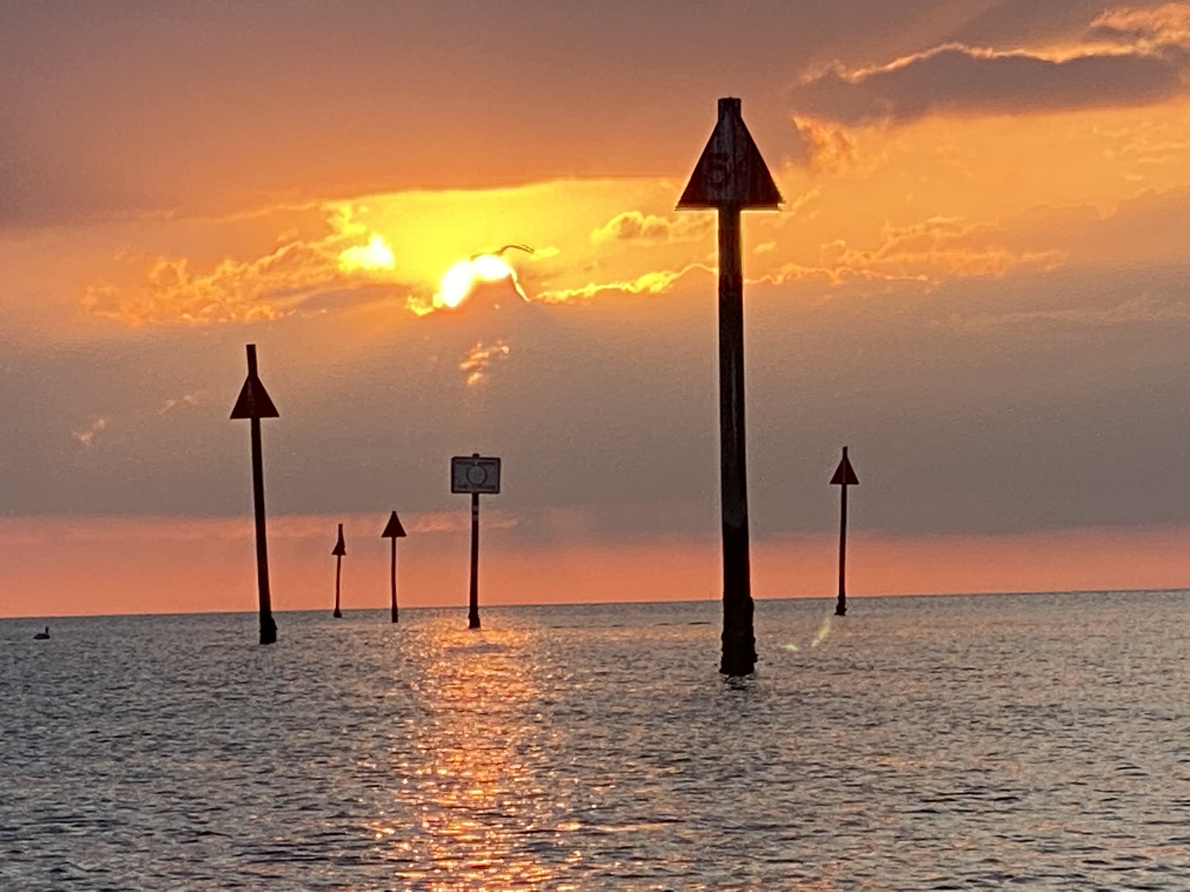 Orange sunset beyond the navigation markers at Aripeka Harbor
