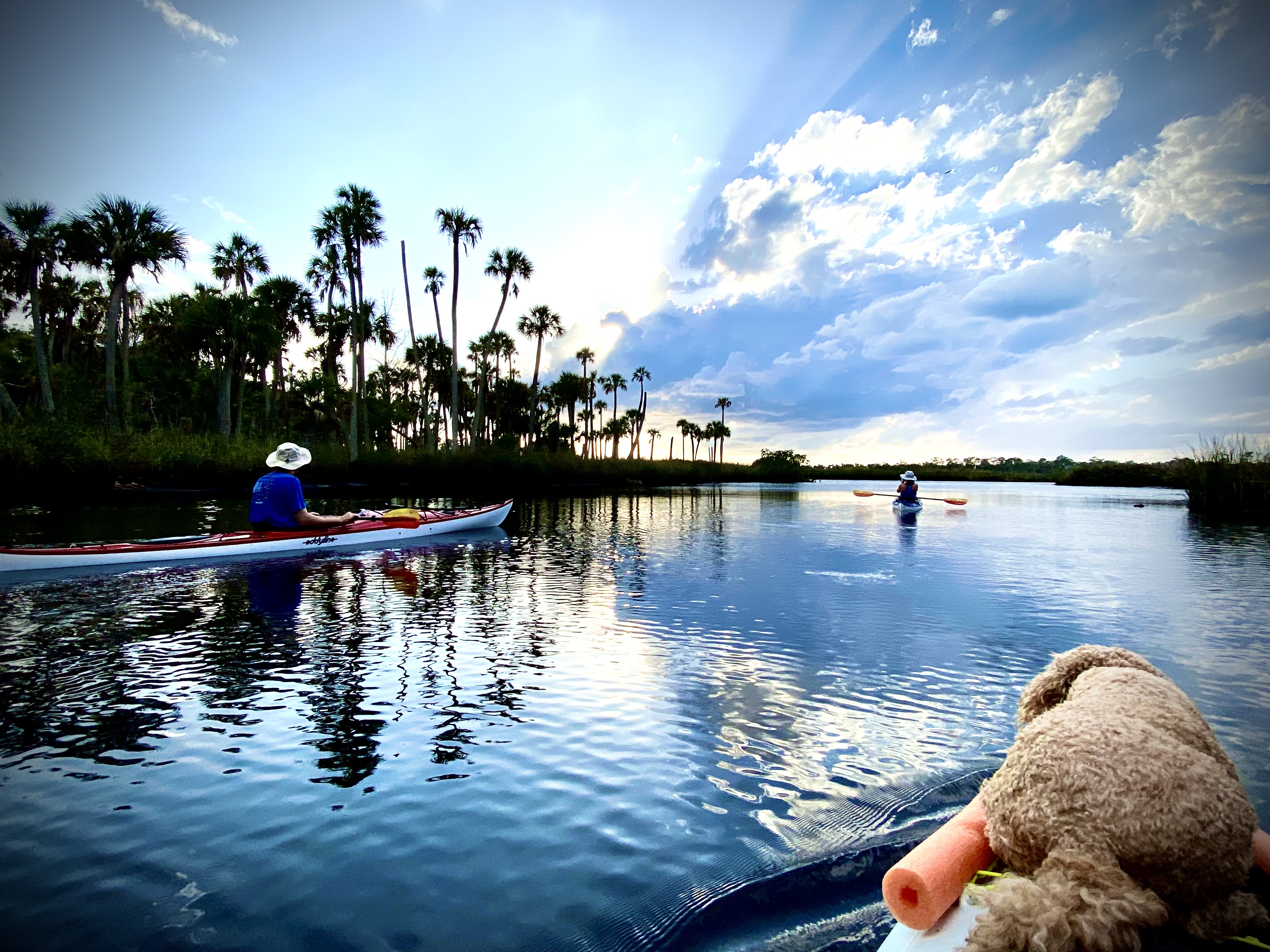 Kayakers and clouds reflected in calm water