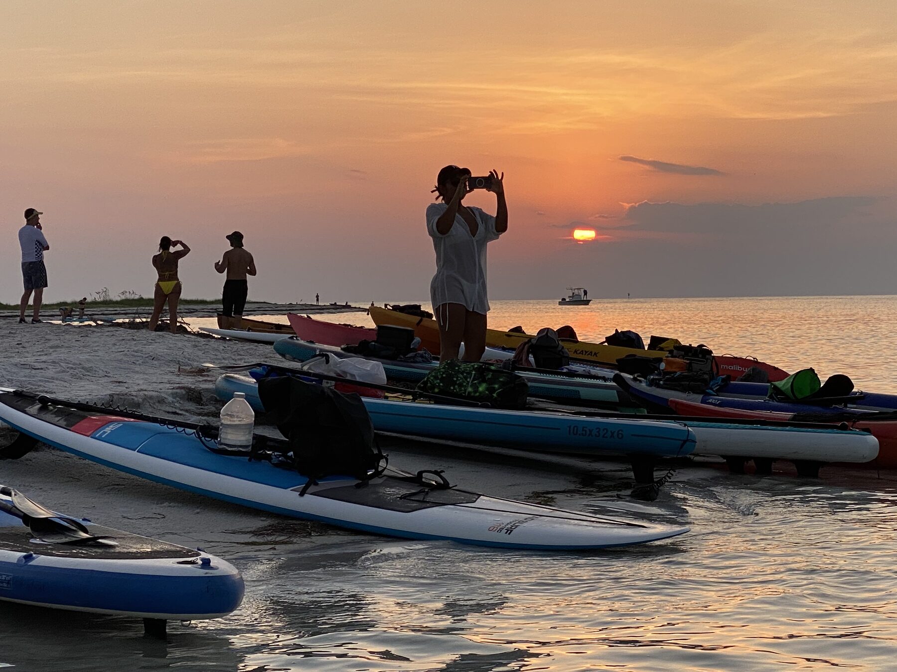 Paddlers photographing an orange sunset