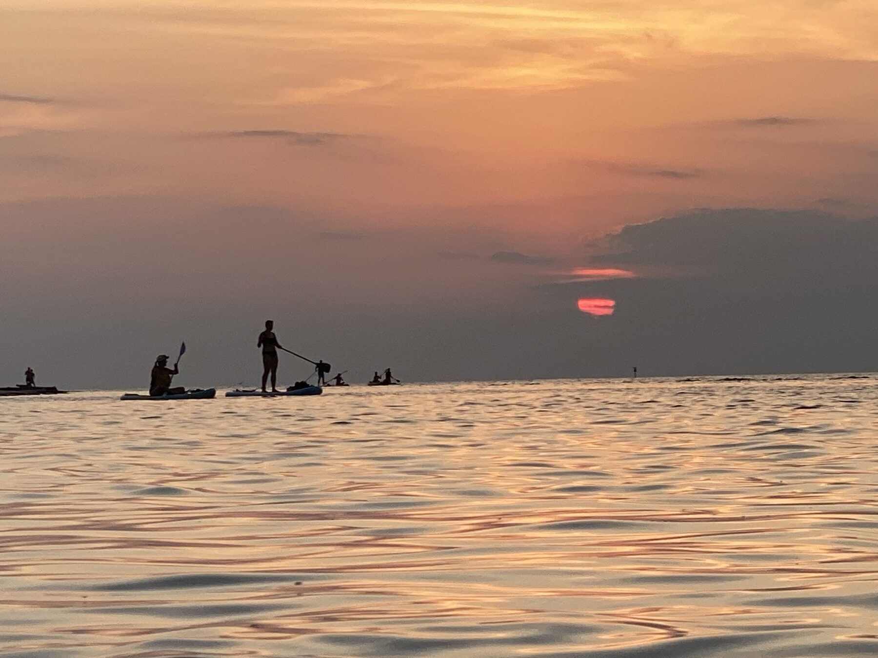 Paddlers silhouetted beneath the final red sunset