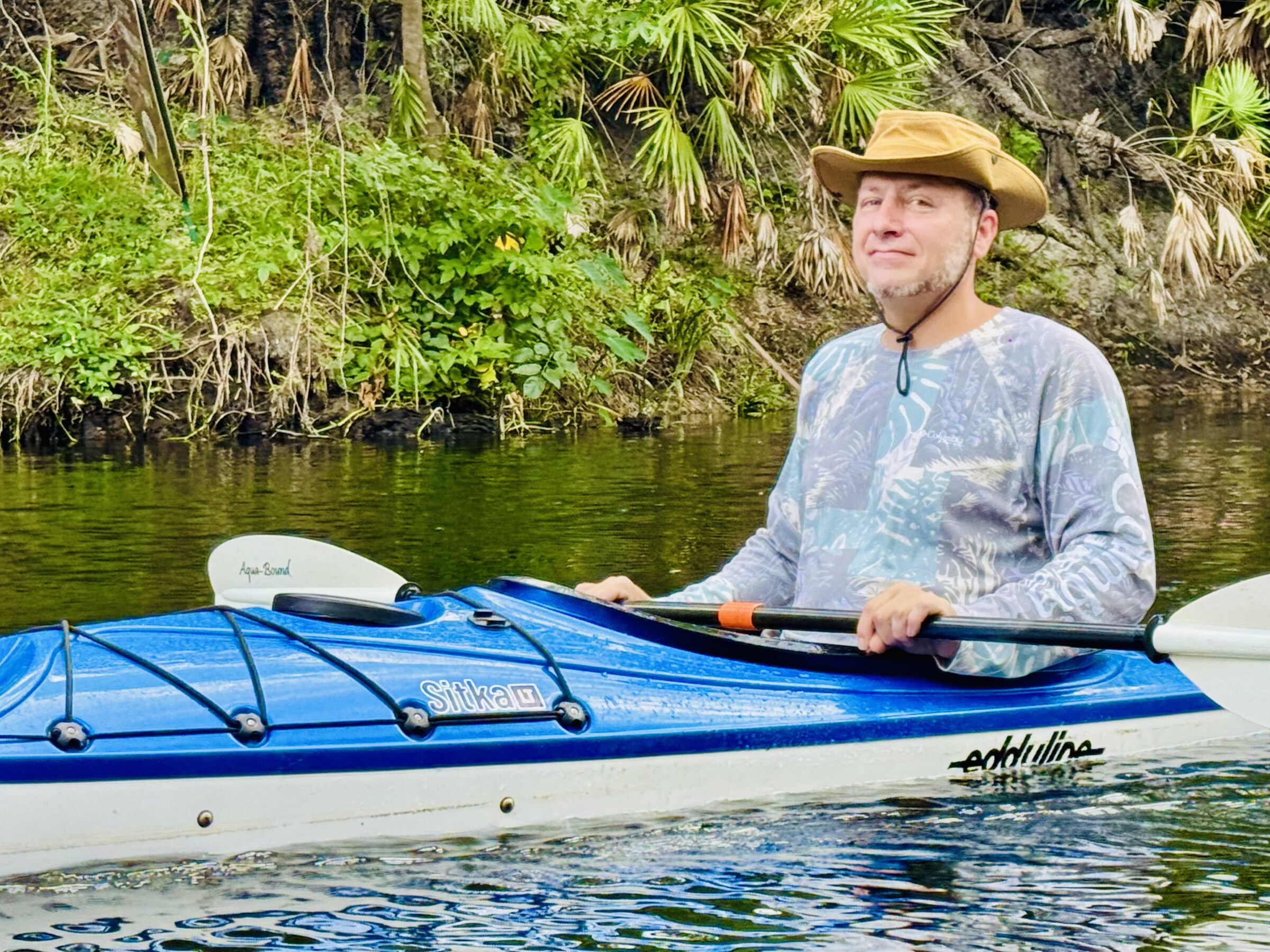 Paddler smiling from a blue kayak