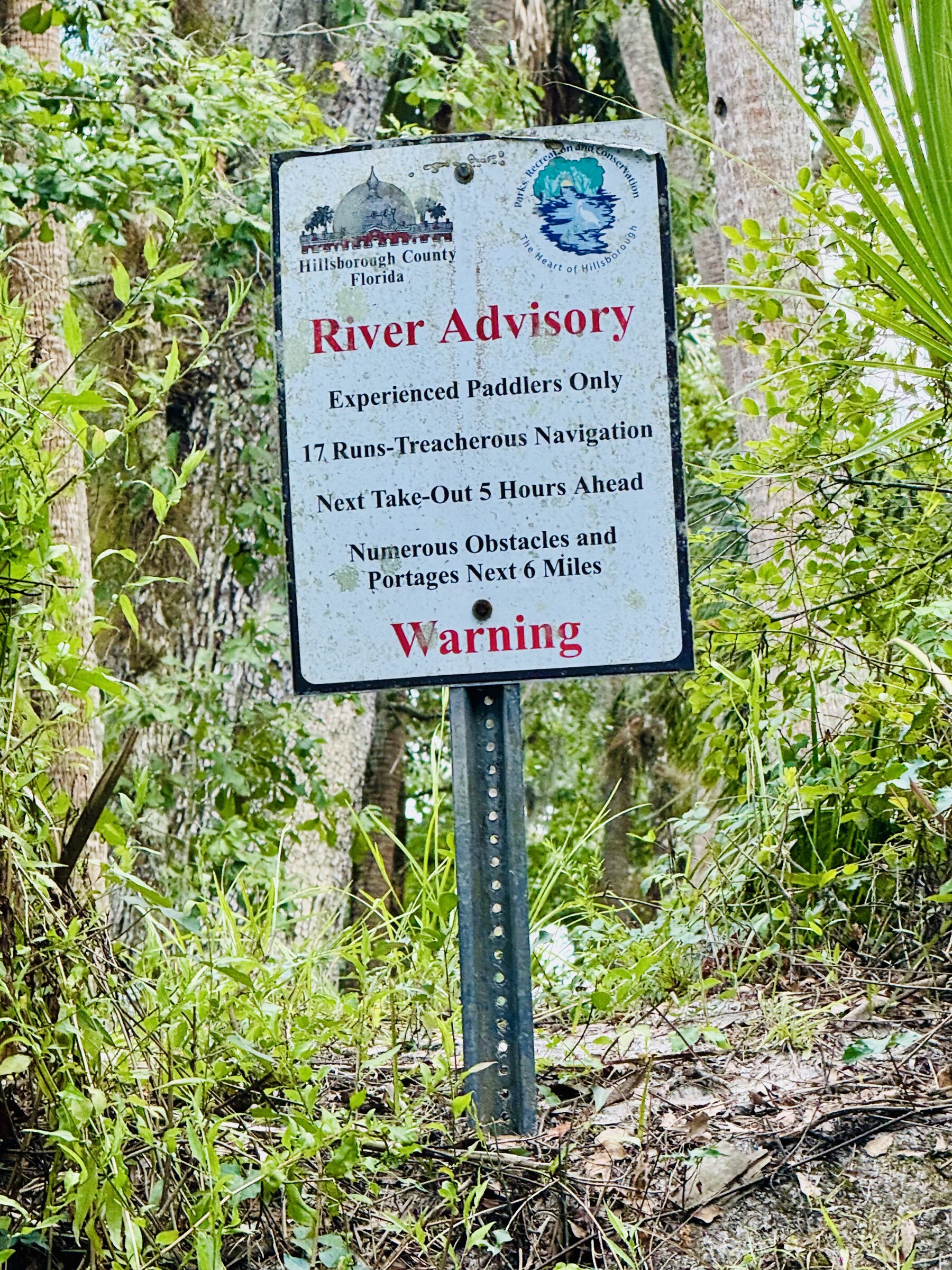 River advisory sign beside the wooded river