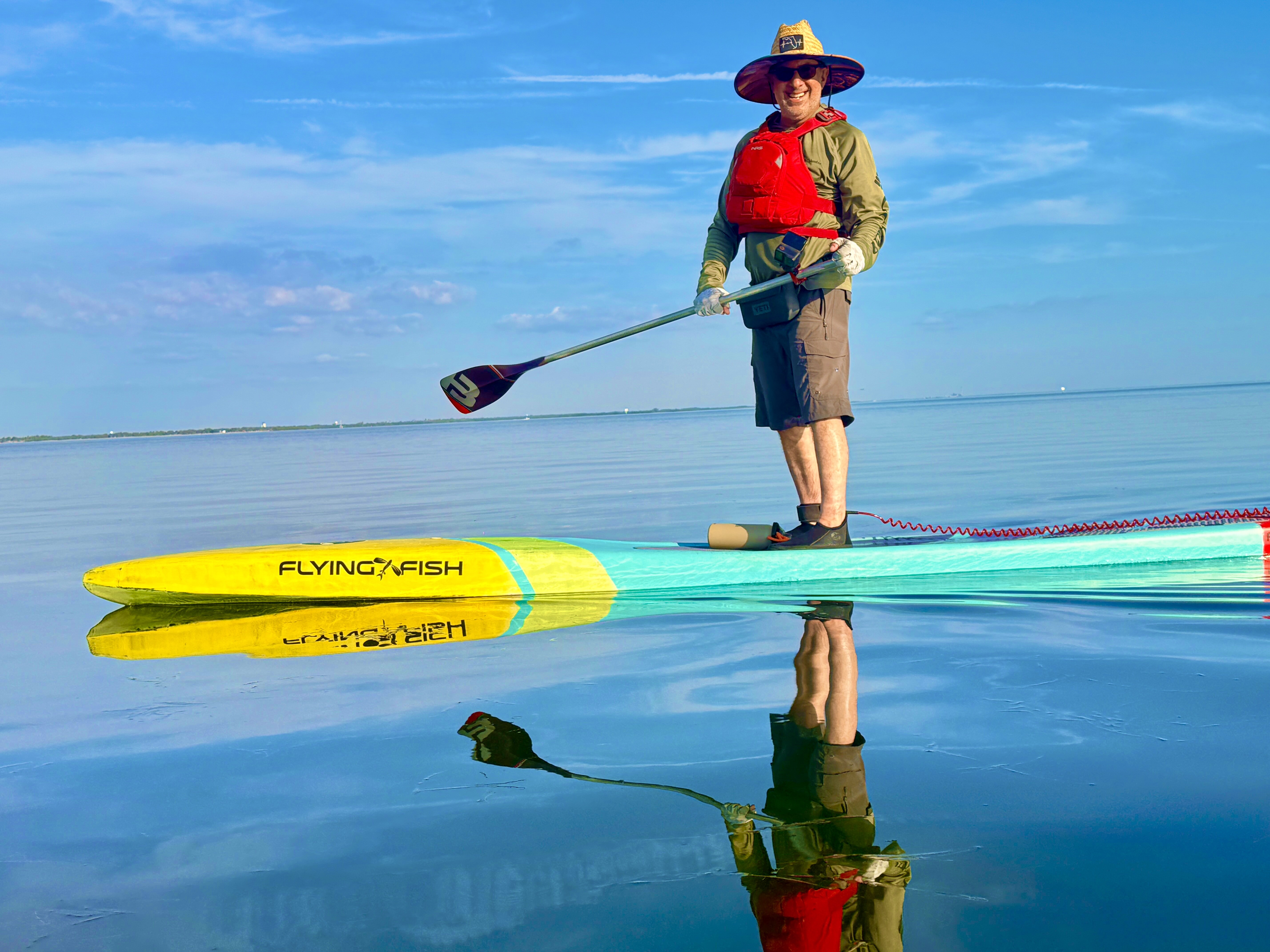 Robbie and his paddleboard perfectly reflected in glassy water