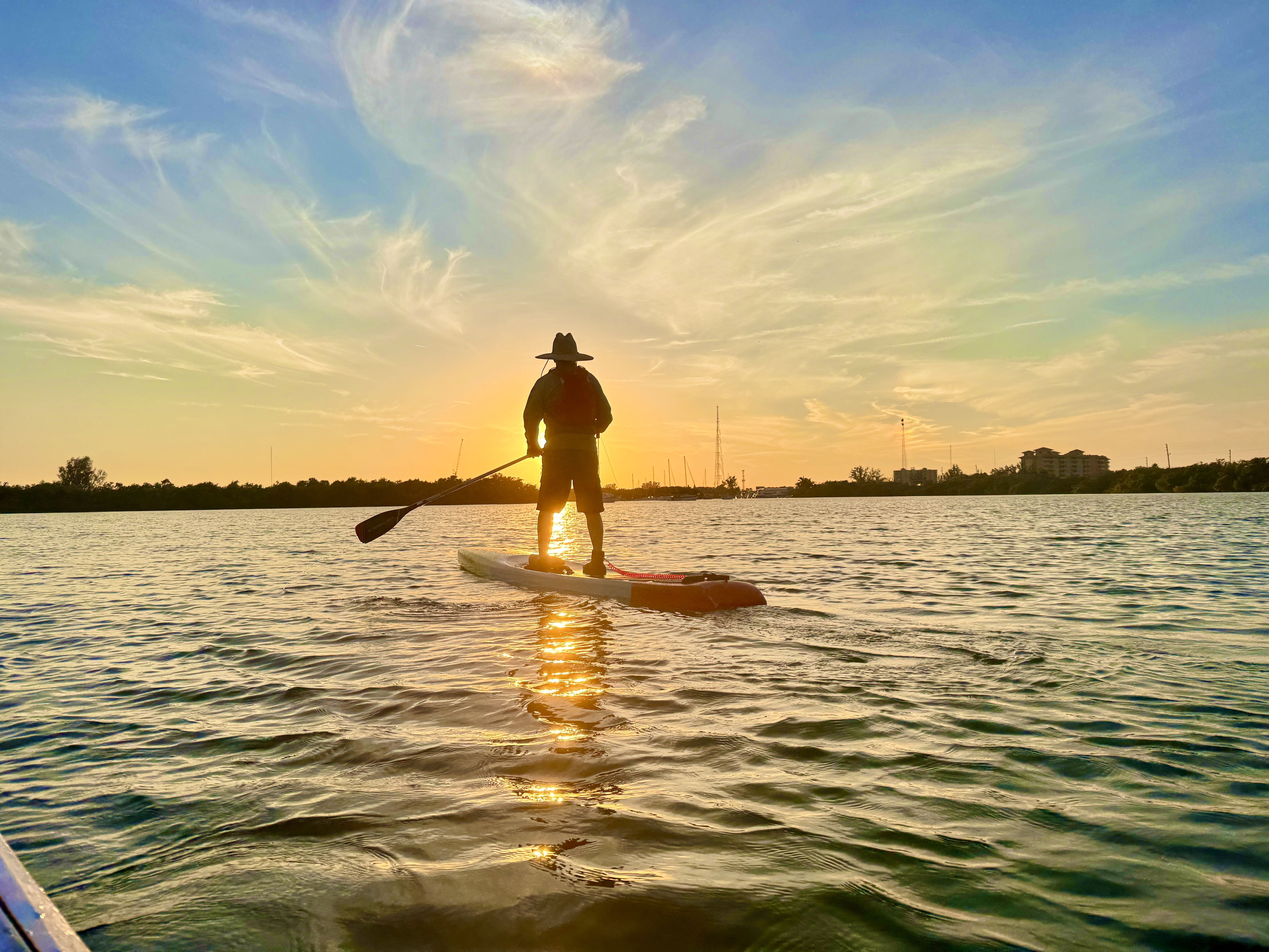 Robbie paddleboarding toward the late afternoon sun