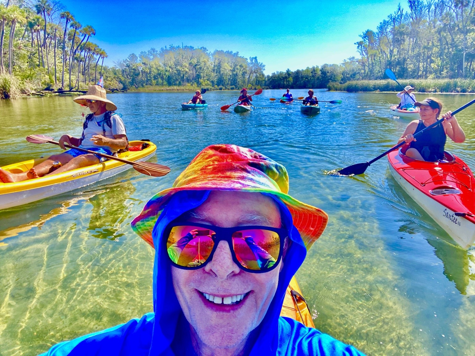 A cheerful mid-paddle selfie with the birthday group spread out on the river behind.