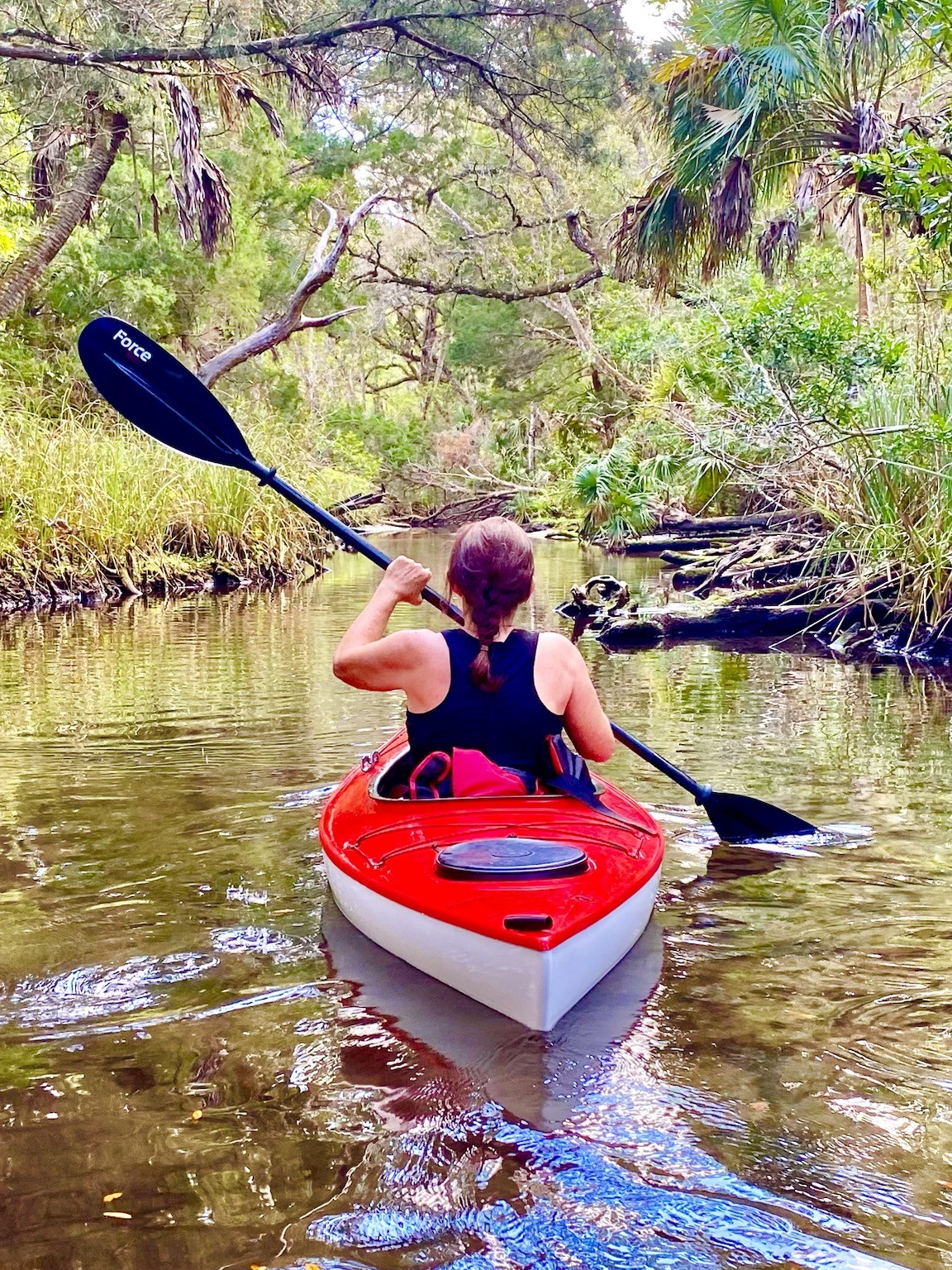 A red kayak slipping through one of the narrower shaded side channels.