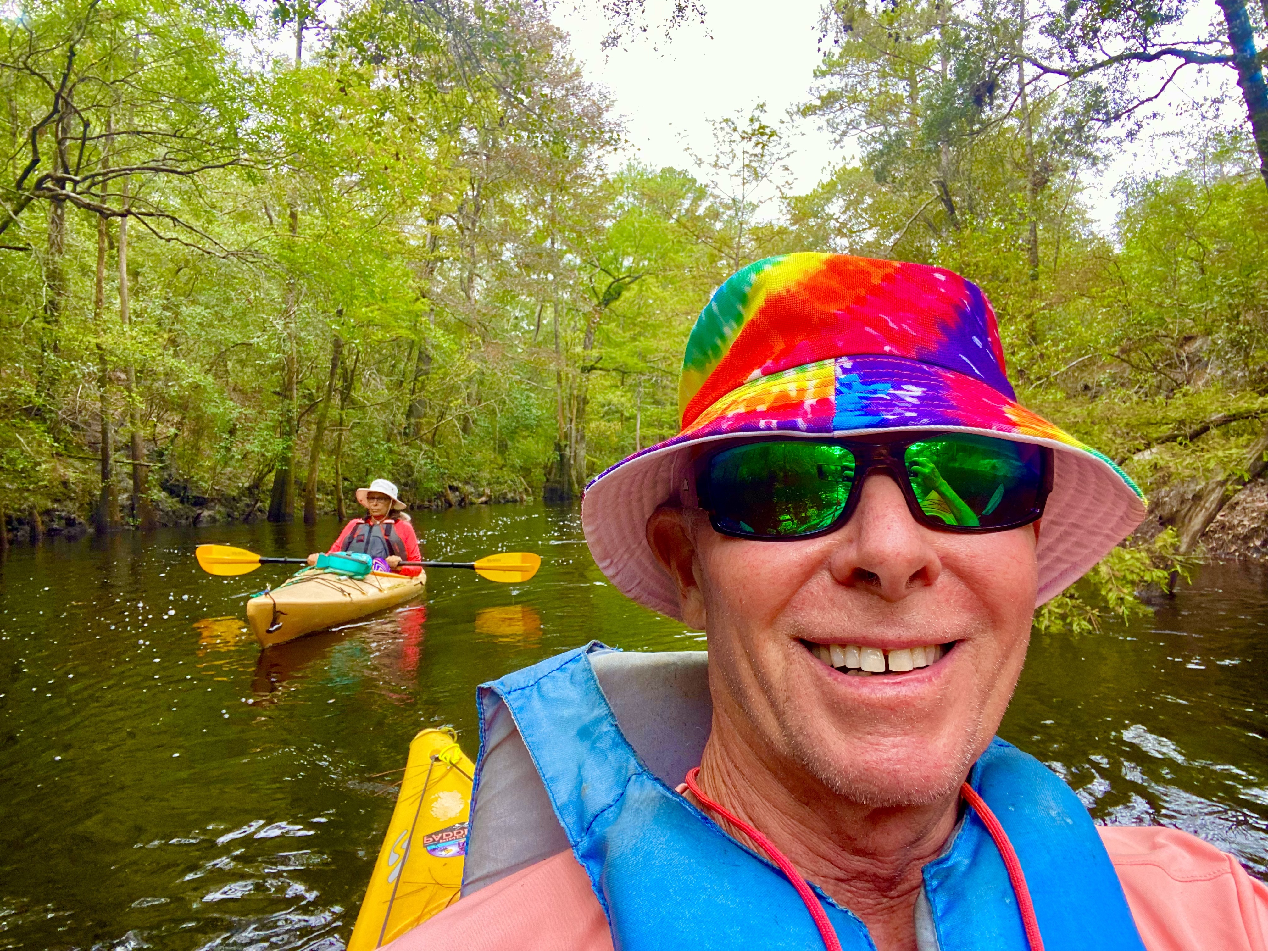 Tim smiling from his kayak with other paddlers behind him on the Sopchoppy River