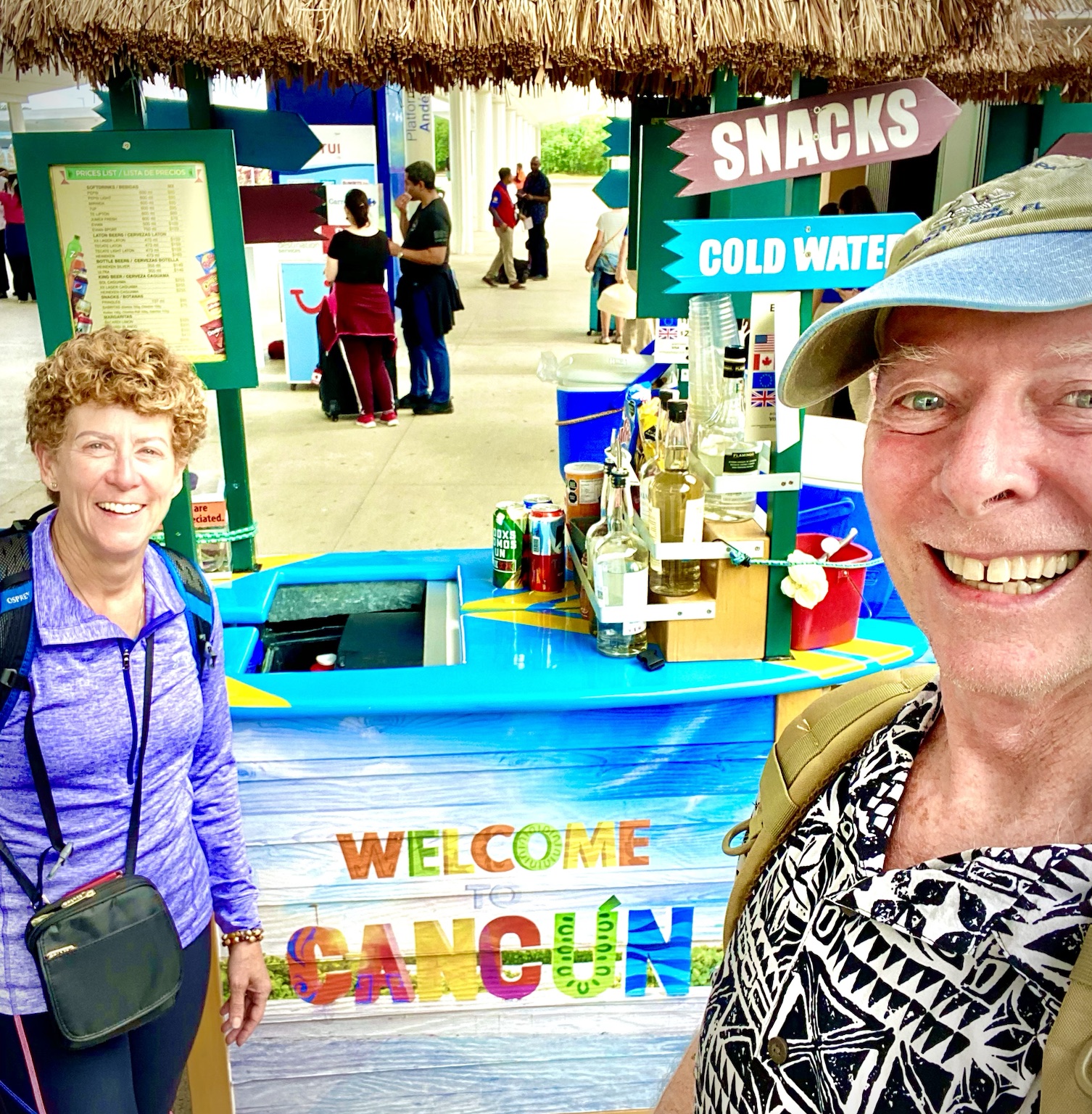 Arriving in Cancún, with the colorful airport welcome stand behind them.
