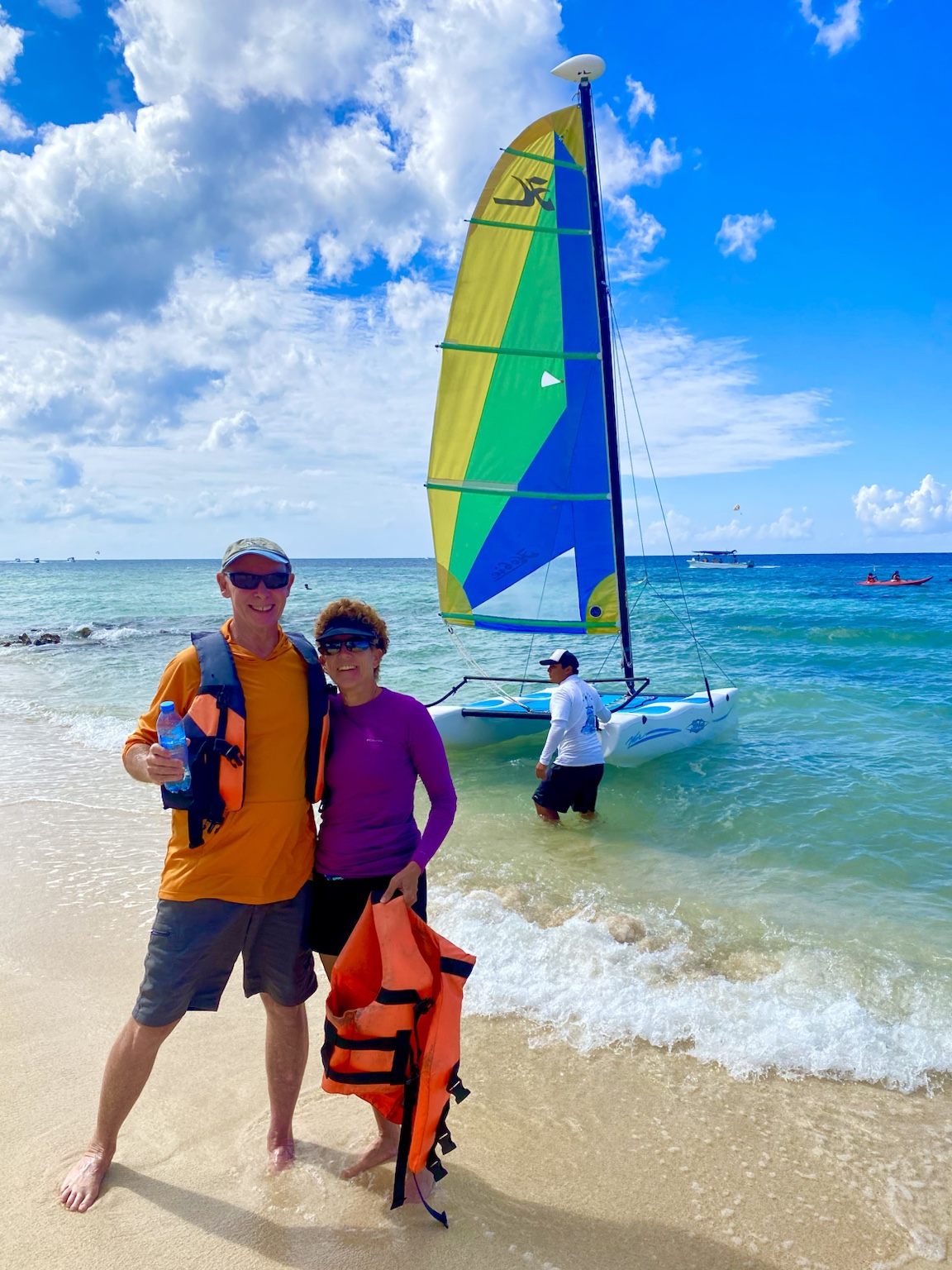 Ready for a sailing adventure beside a brightly colored catamaran on the beach.