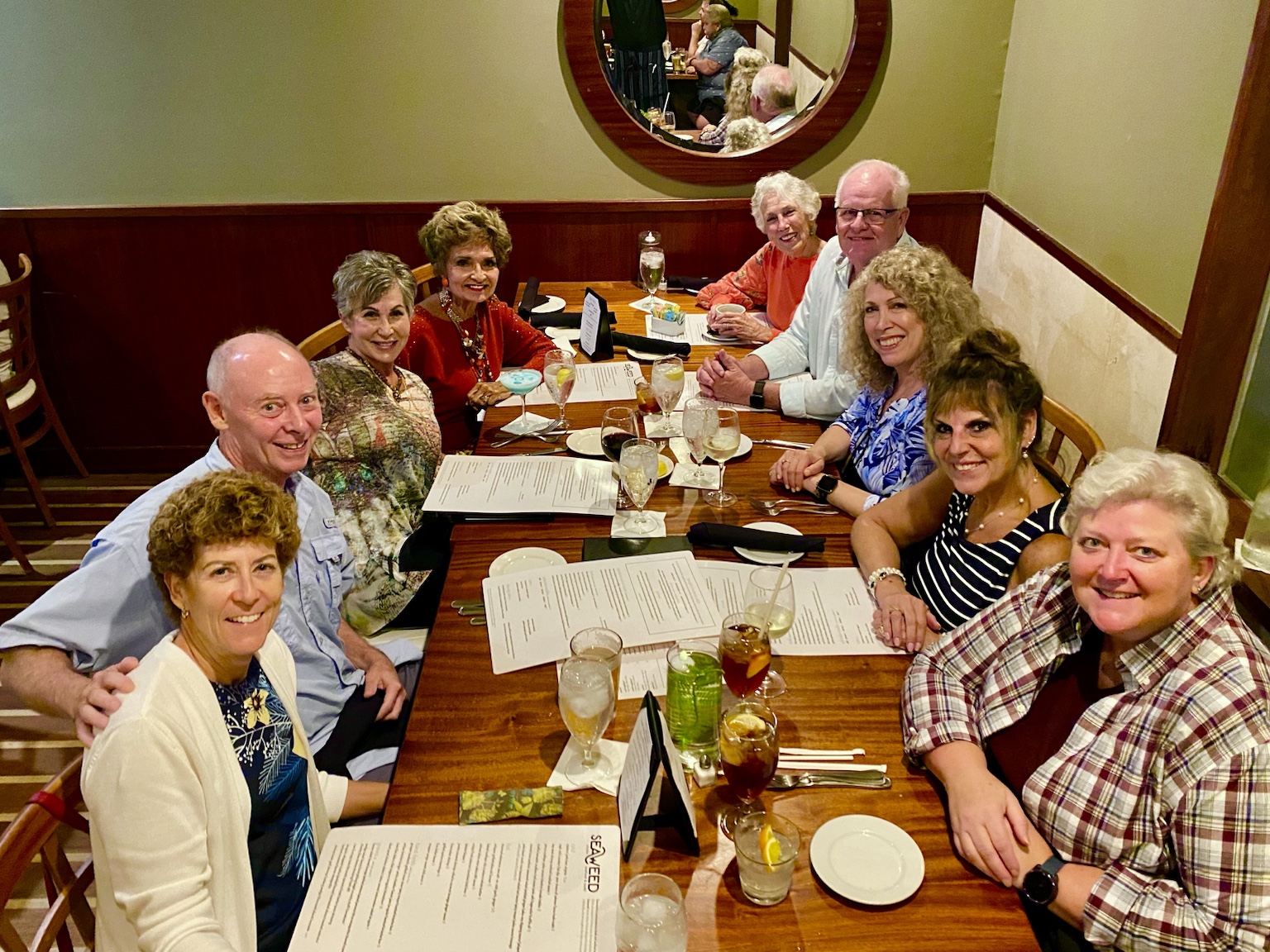 A large dinner gathering with family and friends around a long restaurant table.