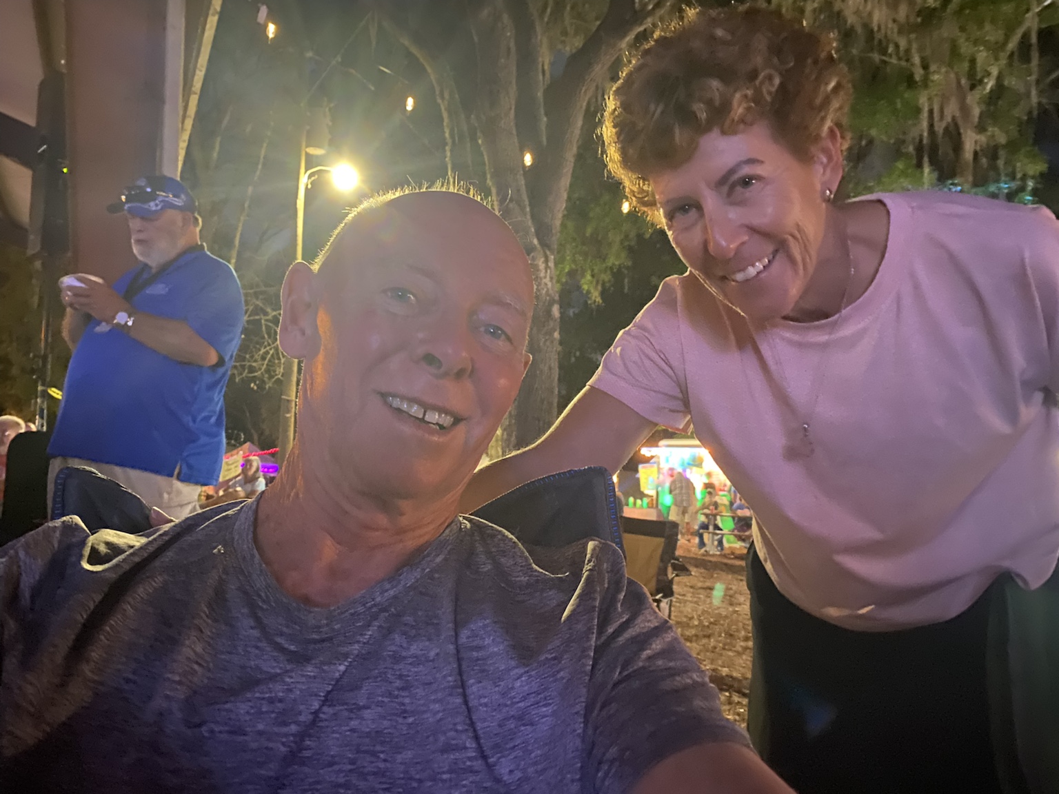 A relaxed nighttime selfie while enjoying an outdoor music event.