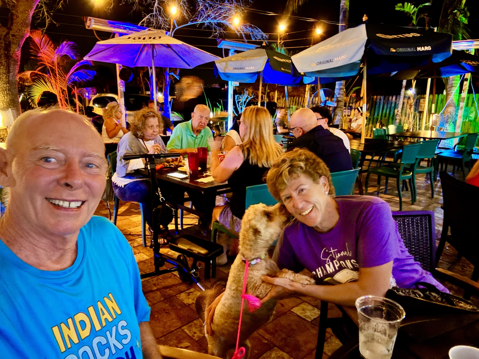 Buddyboy gives Kym a kiss during dinner on a colorful outdoor patio.