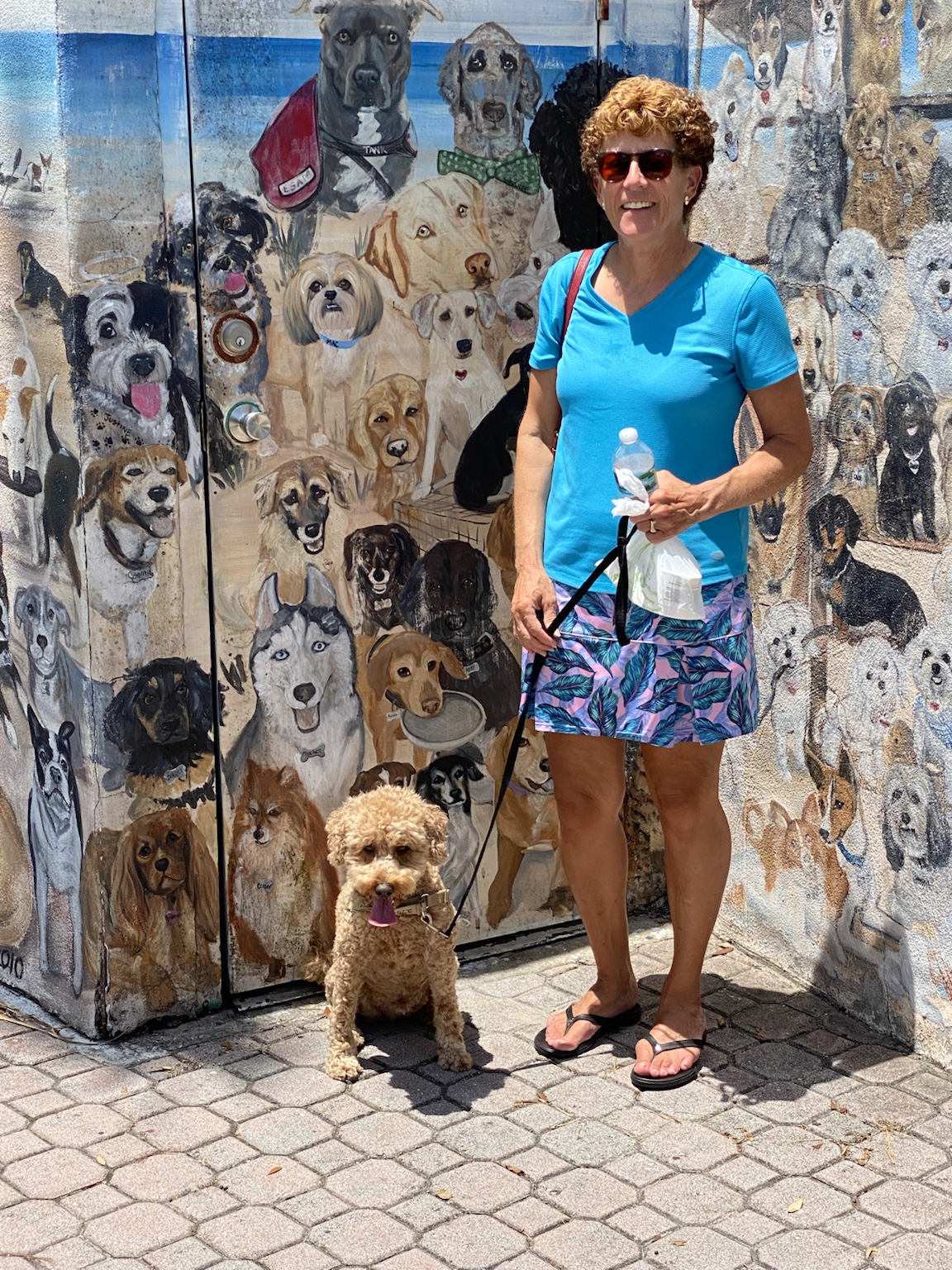 Kym and Buddyboy pose in front of a mural filled with painted dogs.