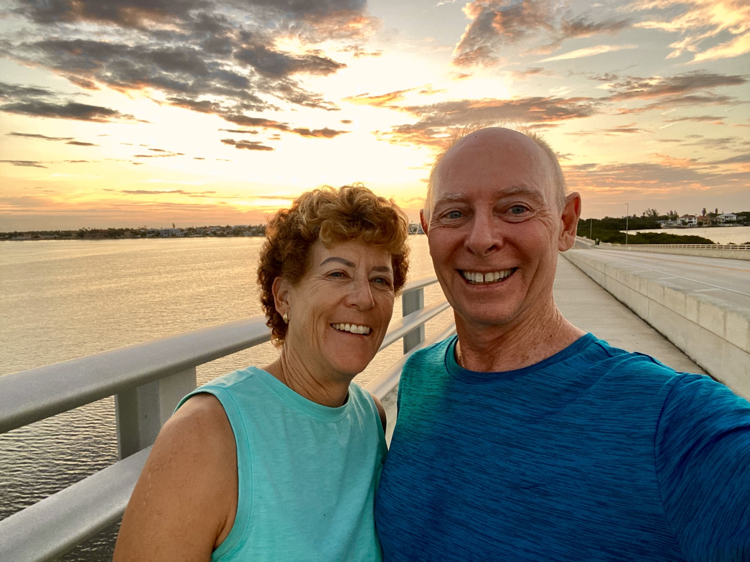 A sunset selfie from a bridge overlooking calm coastal water.