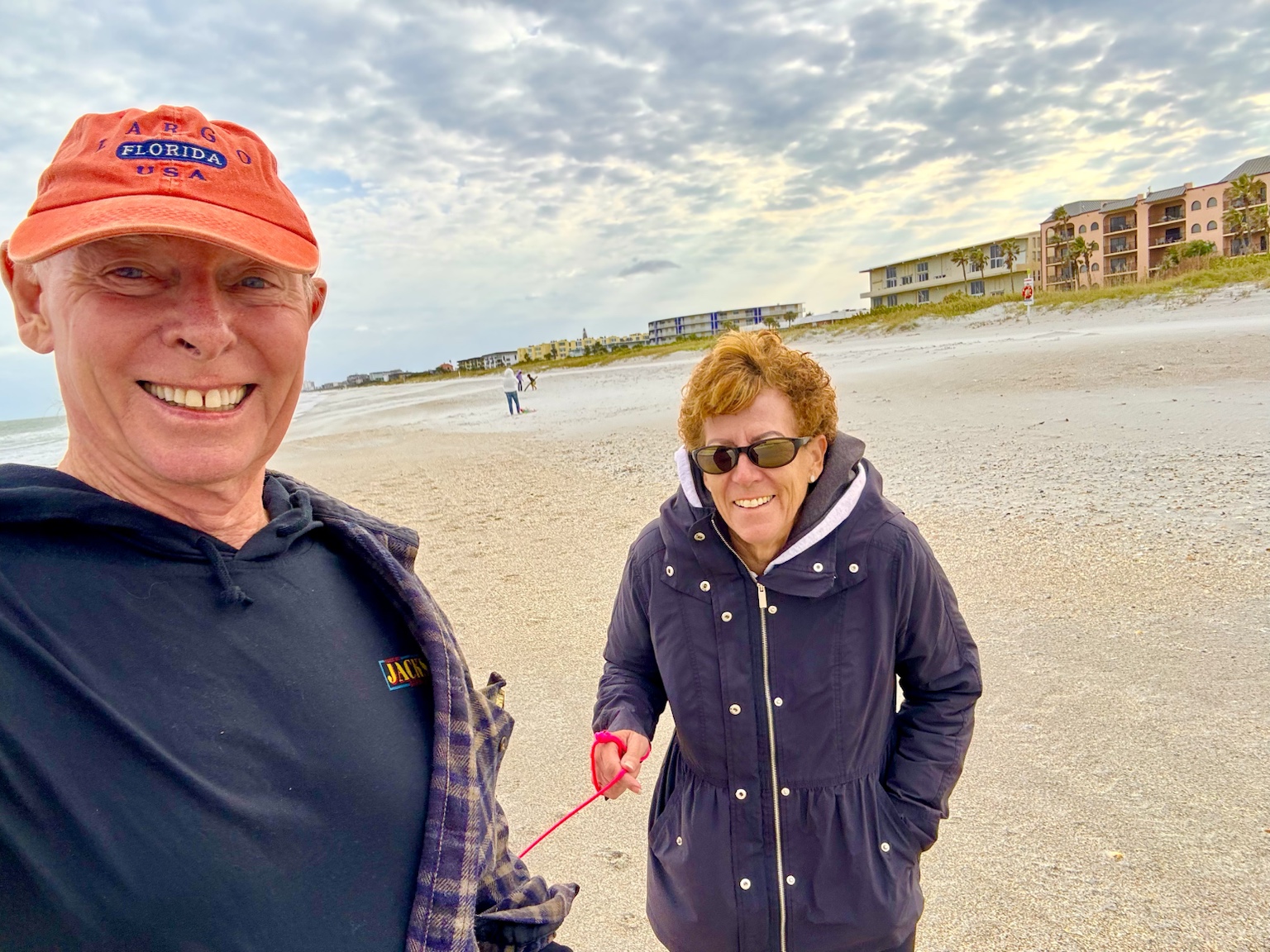 Bundled up for a cool, breezy walk along a wide Florida beach.