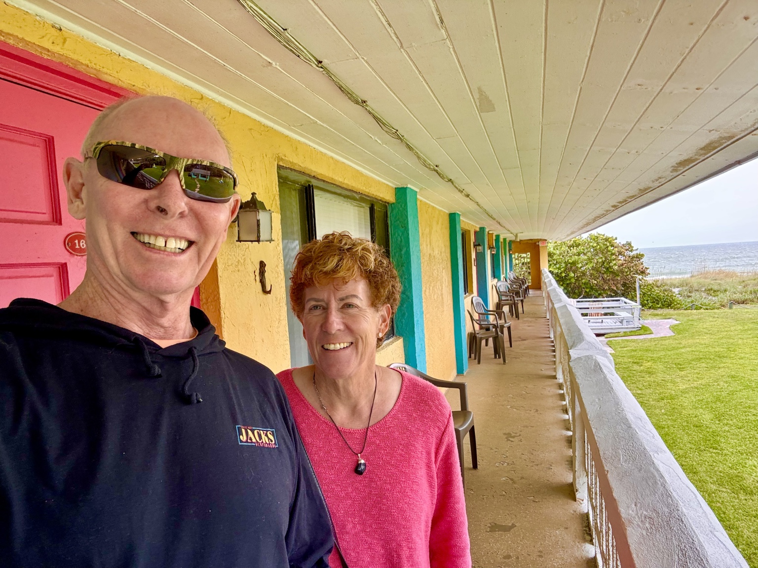 Tim and Kym outside their colorful beachfront lodging with the ocean just beyond the balcony.