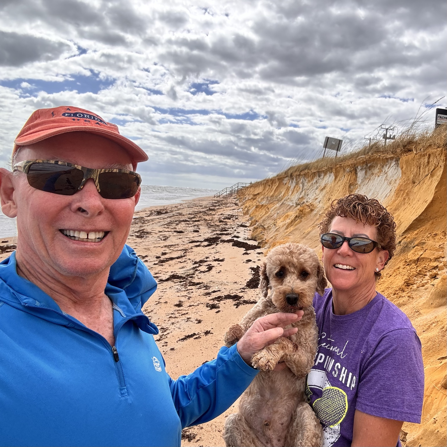 Tim, Kym, and Buddyboy pause for a family selfie beside the eroded beach bluffs.