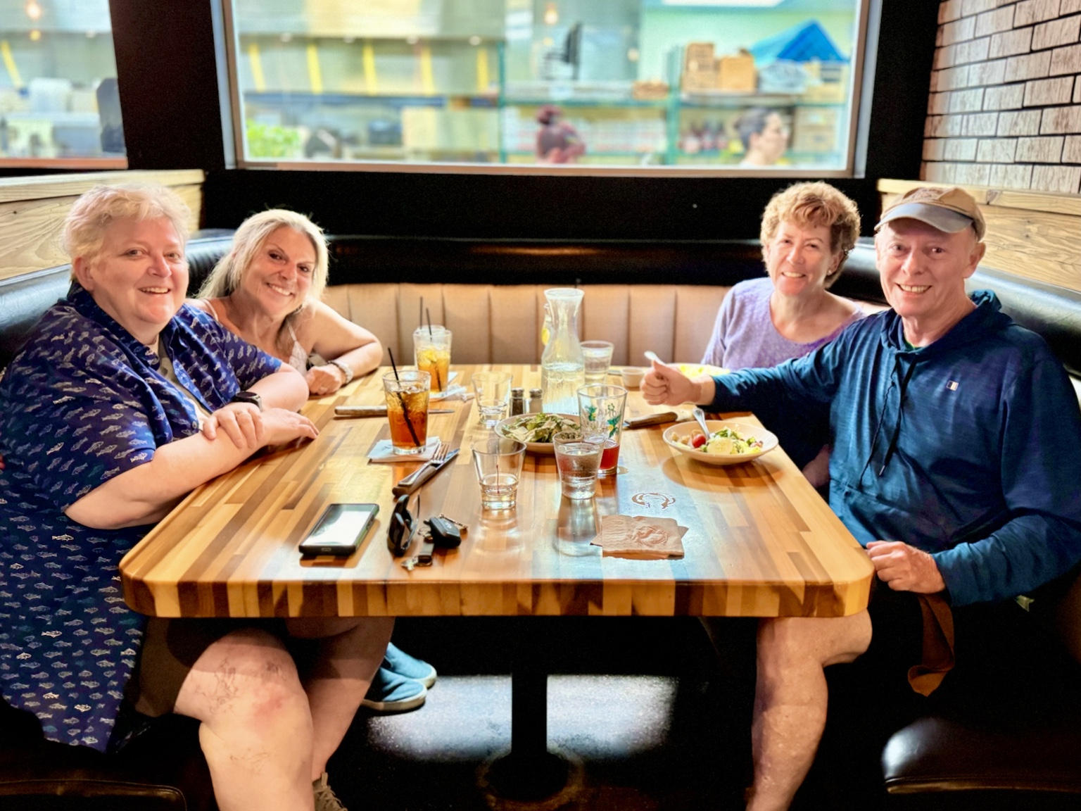 A relaxed restaurant meal with family, gathered around a booth and smiling for the camera.