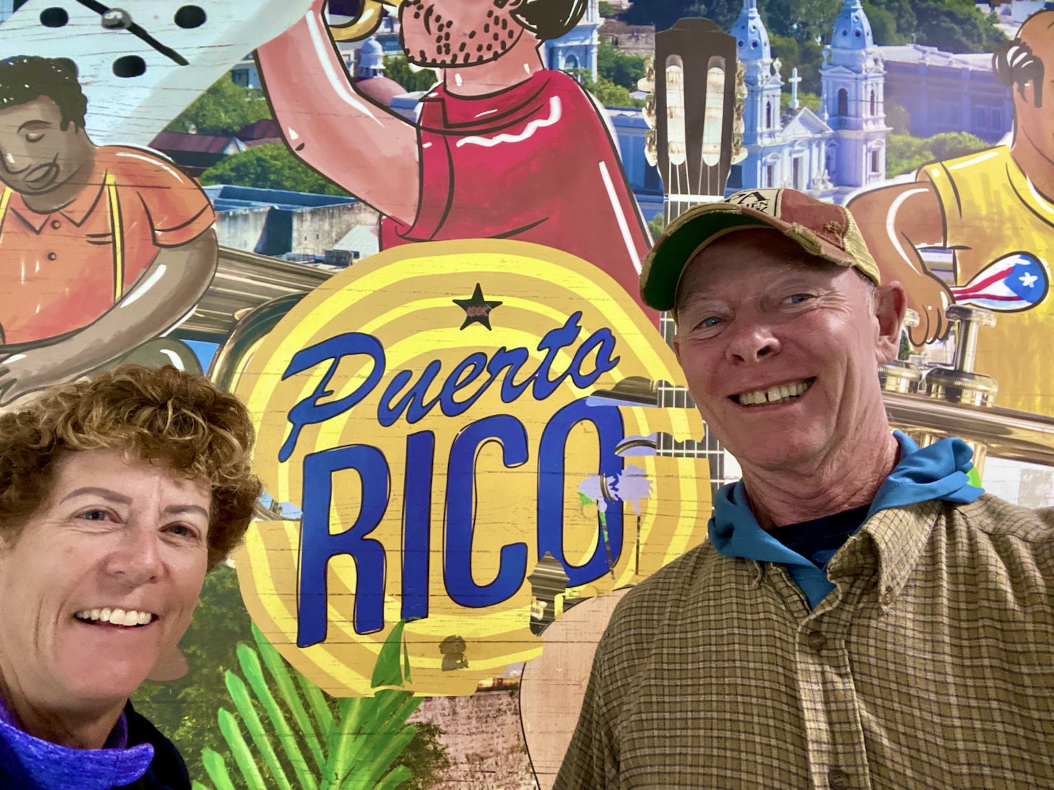 Tim and Kym pose in front of a colorful Puerto Rico mural celebrating the island’s music and culture.